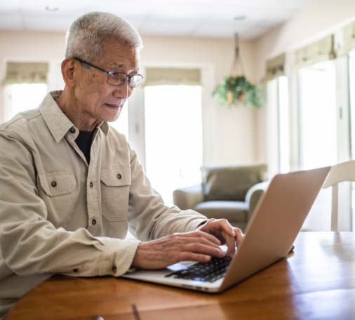 Older man typing on laptop